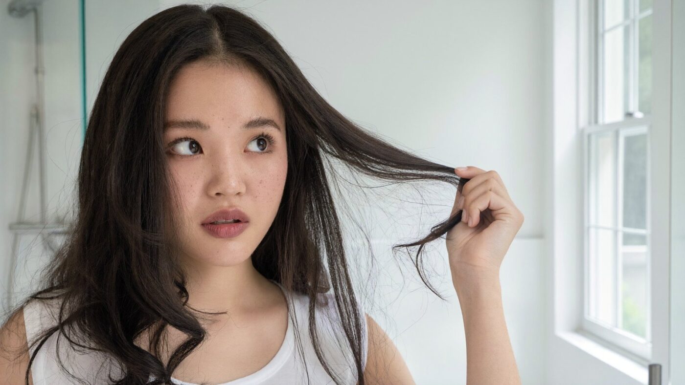 Cô gái Việt xem sợi tóc khô xù khi độ pH của tóc bị lệch