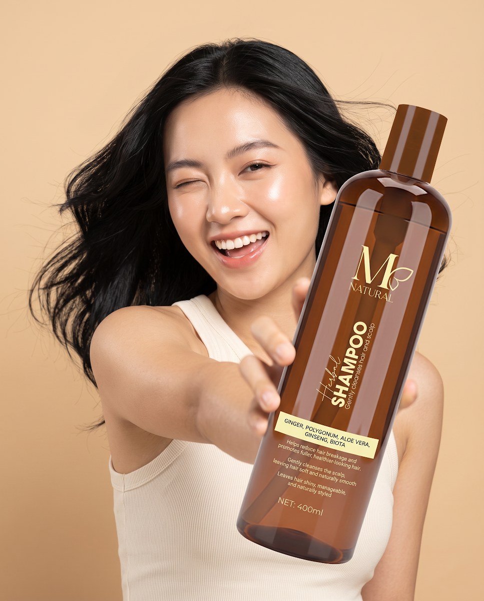 Cô gái Việt trẻ tóc bay cầm chai dầu gội thảo dược M Natural 400ml
