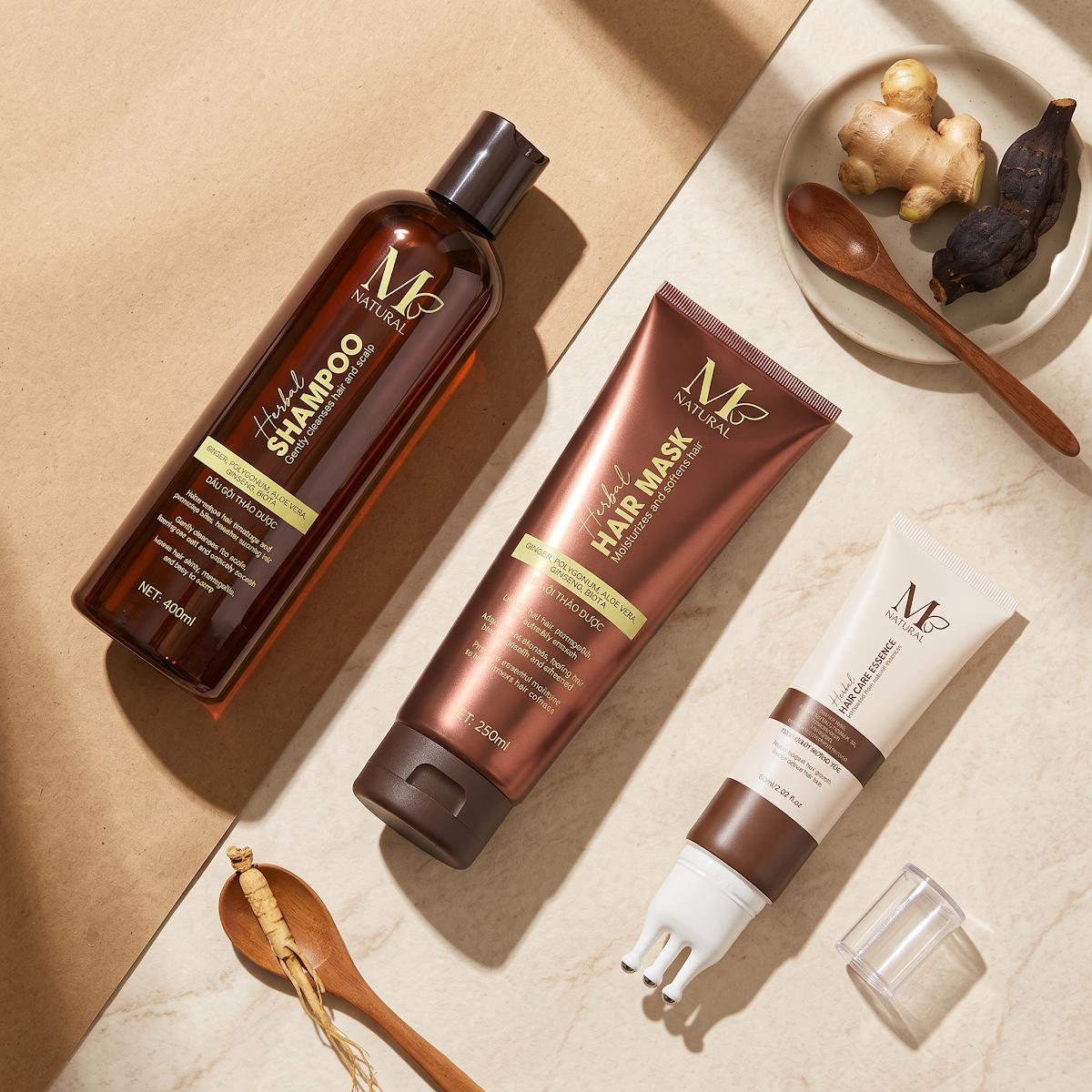 Bộ ba sản phẩm chăm sóc tóc M Natural bày cùng thìa gỗ và gừng