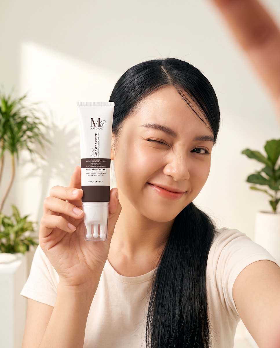 Cô gái Việt trẻ tươi cười cầm tinh chất dưỡng tóc M Natural 60ml