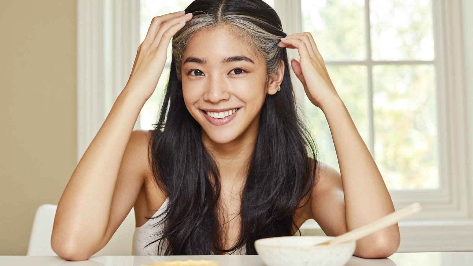 Người phụ nữ Á Đông điểm vài sợi tóc bạc, nhẹ nhàng vuốt mái tóc trong nắng sớm