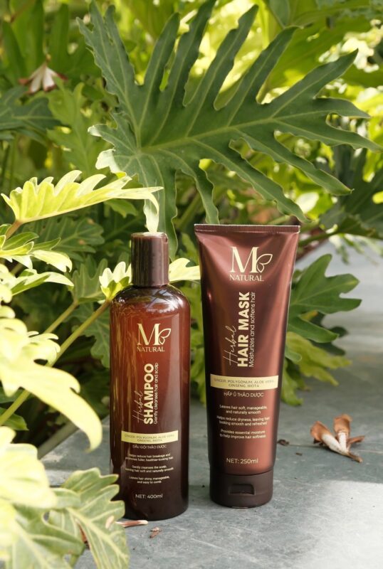 Chai dầu gội và tuýp kem hấp ủ M Natural giữa tán lá xanh