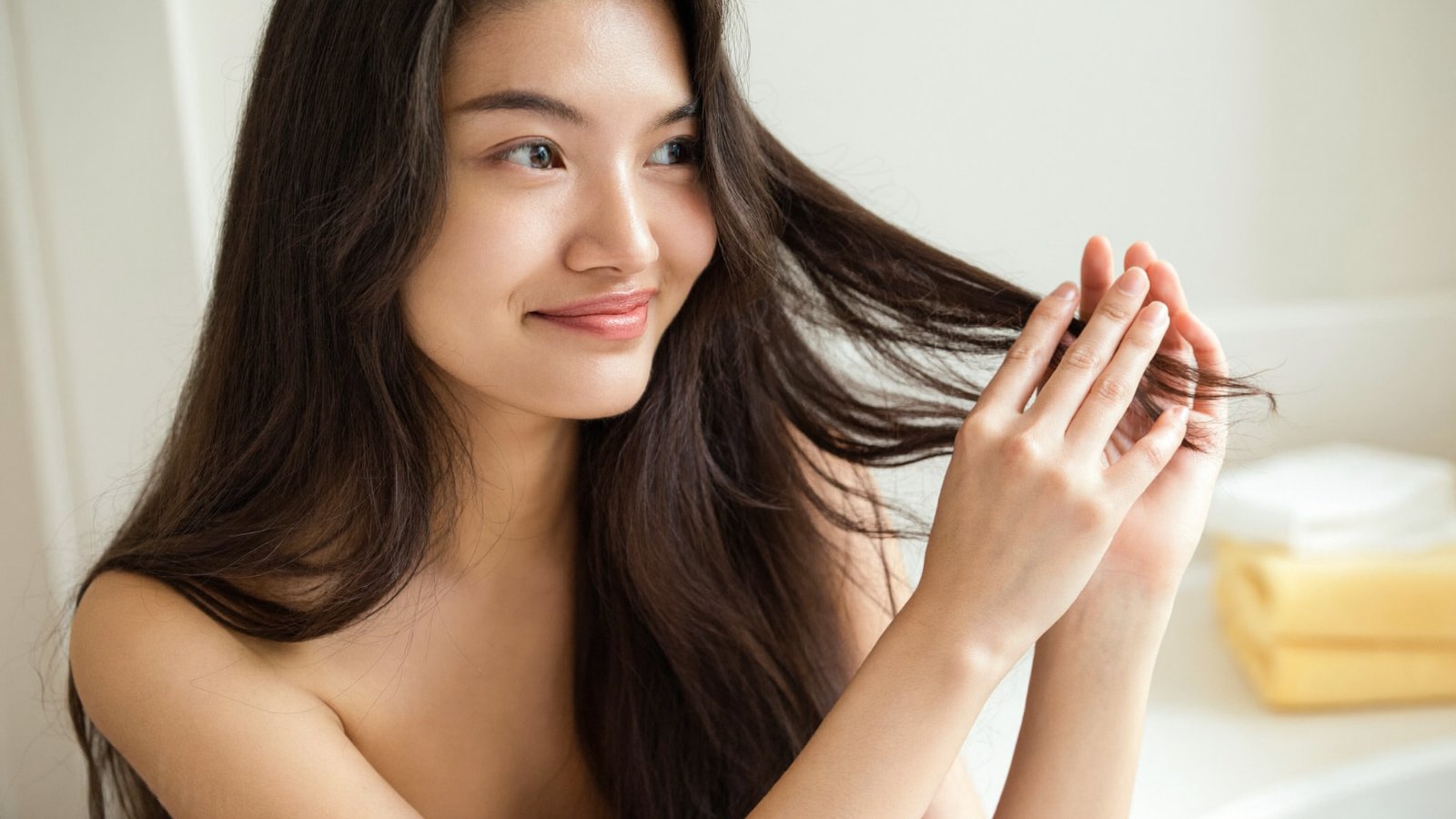 Cô gái vuốt nhẹ phần đuôi tóc dài, chăm sóc tóc sau hóa chất